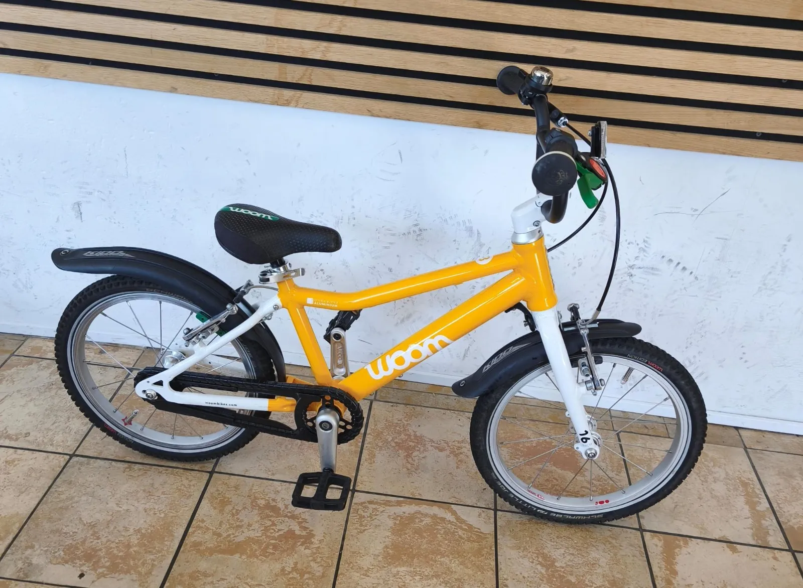 Woom Kinderrad in Gelb-Weiß mit 16-Zoll-Laufrädern, Schutzblechen und Kettenschutz